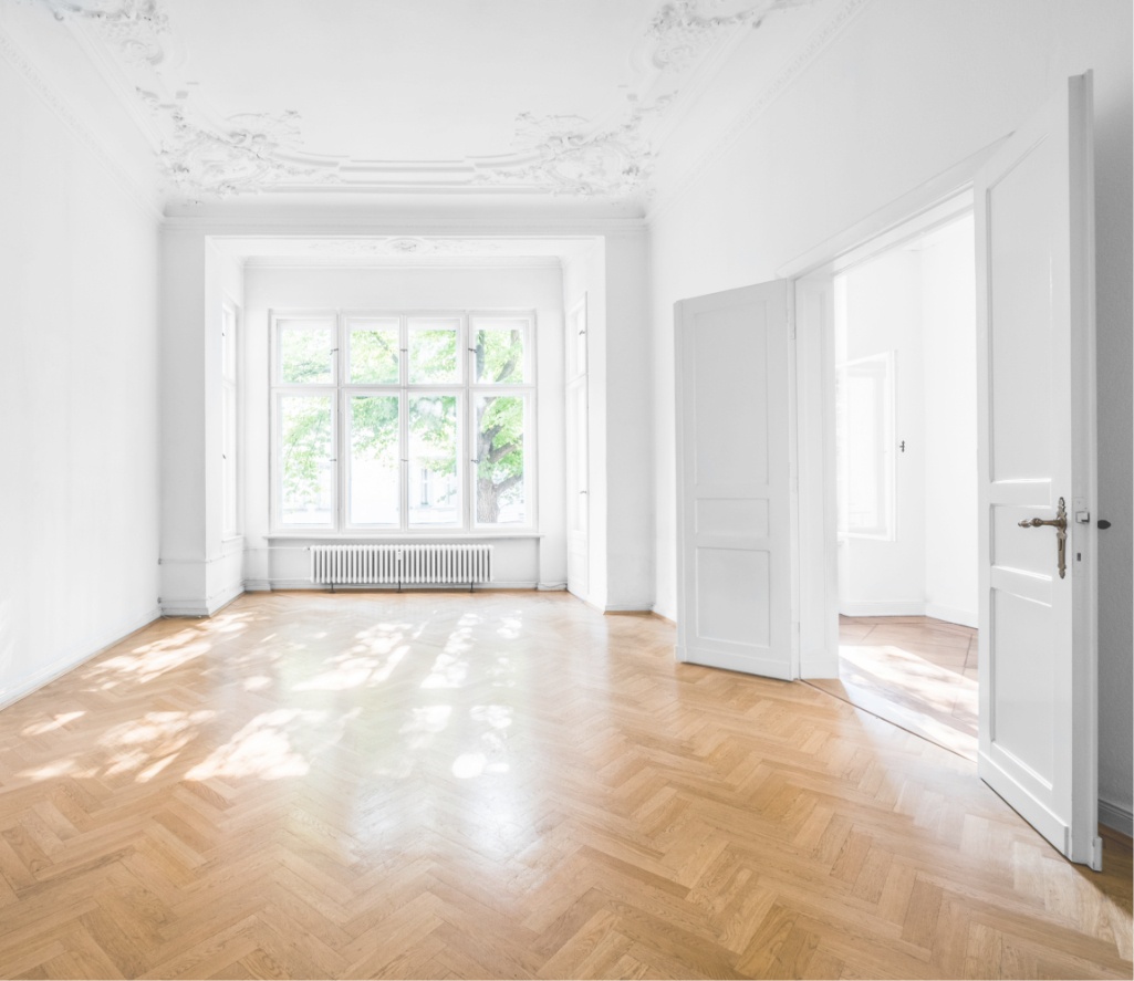 Helles, leeres Zimmer mit Fischgrätparkett und Stuckdecke.