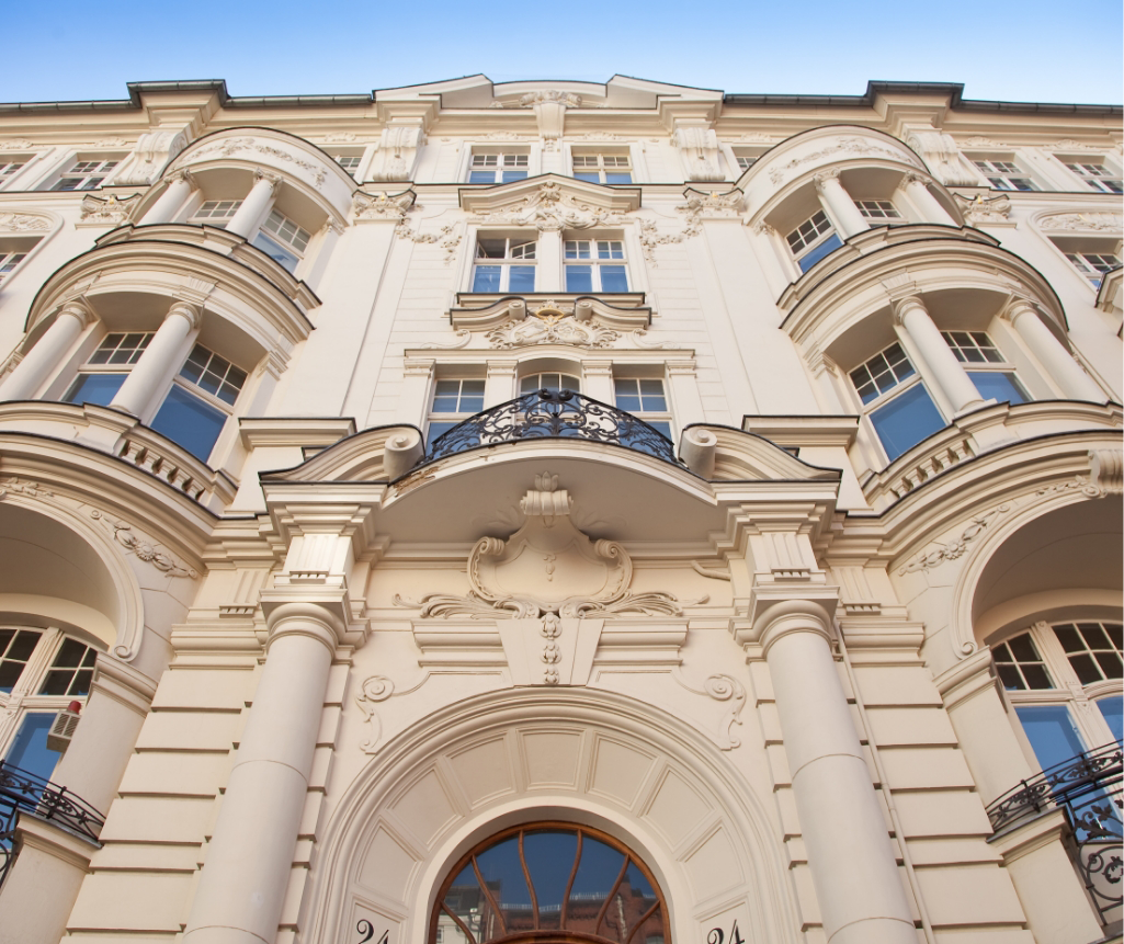 Von unten fotografierte Fassade eines Altbaus mit Balkon und Stuckverzierungen.